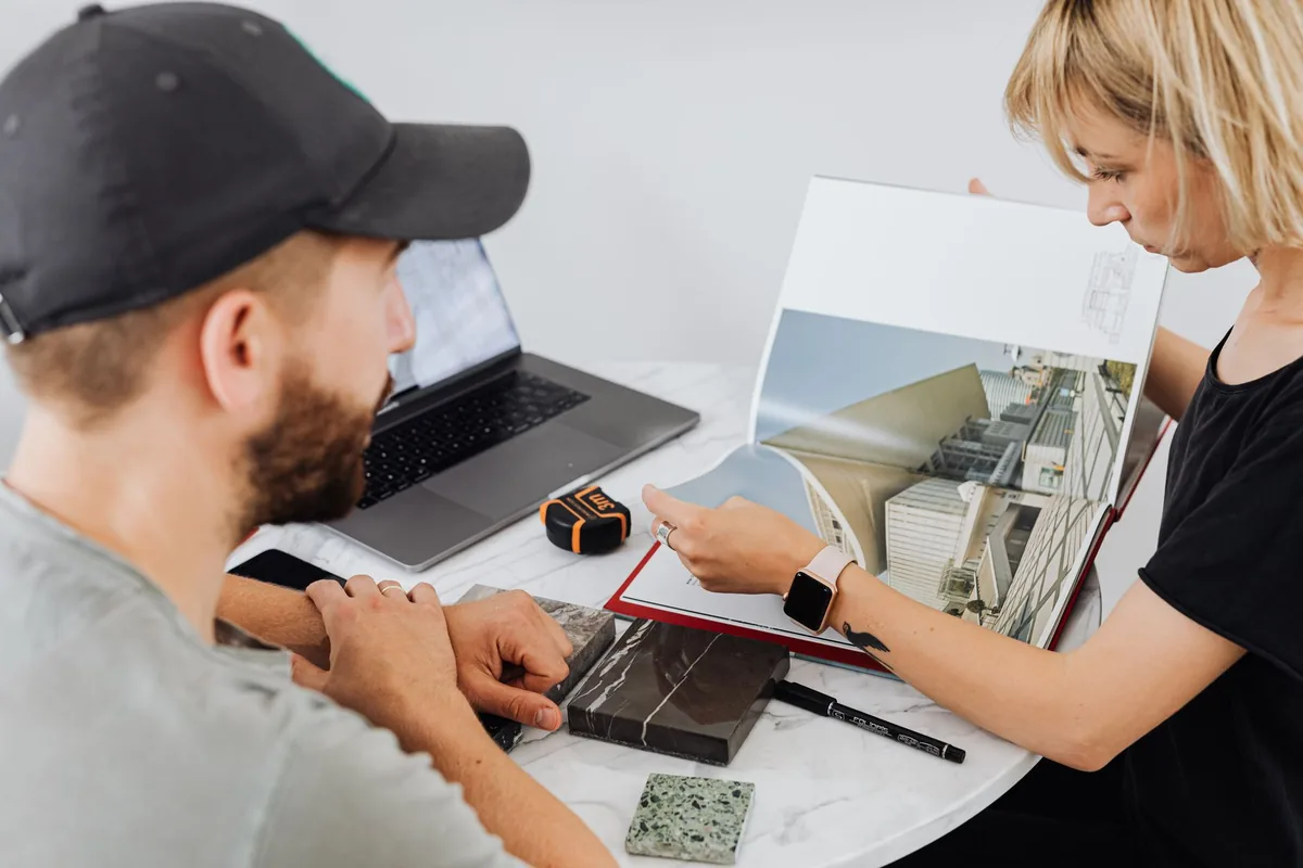 Diseñadora revisando muestras de materiales y planos con un cliente