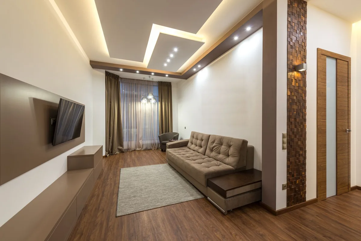 Sala contemporánea en tonos tierra con sofá café, piso de madera y luz cálida